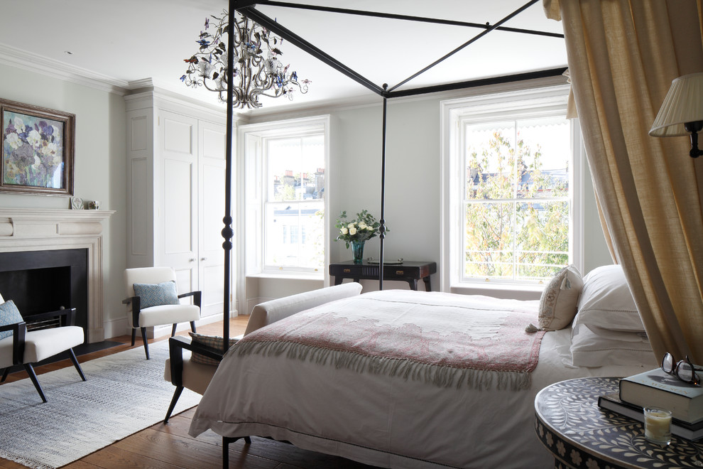 Imagen de dormitorio clásico renovado de tamaño medio con paredes grises, suelo de madera en tonos medios, todas las chimeneas, marco de chimenea de piedra y suelo marrón