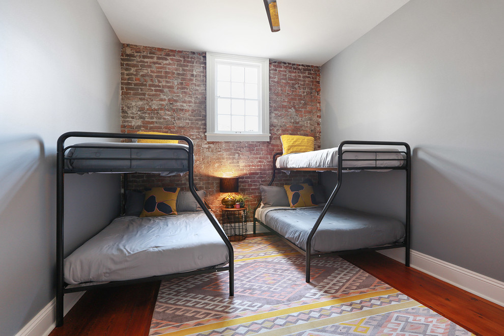 Photo of an industrial grey and brown bedroom in New Orleans with grey walls, medium hardwood flooring and brown floors.