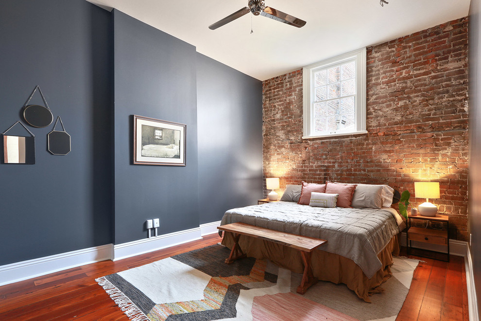 Immagine di una camera da letto industriale con pareti blu, pavimento in legno massello medio e pavimento marrone