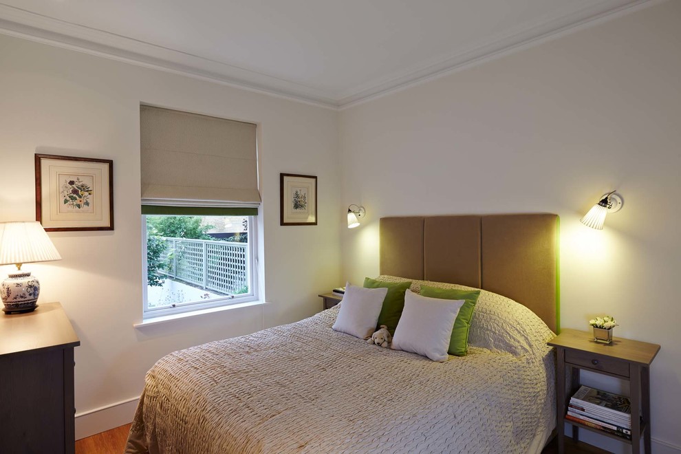 This is an example of a medium sized classic master bedroom in London with beige walls and medium hardwood flooring.