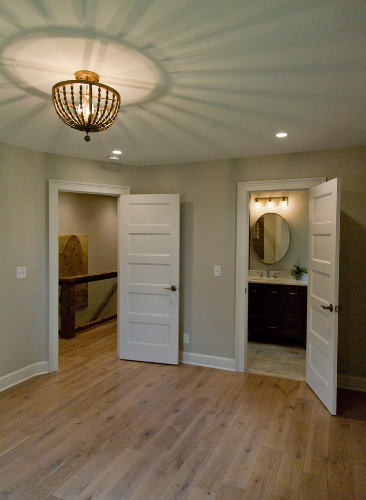 This is an example of a medium sized rural guest bedroom in Kansas City with grey walls, medium hardwood flooring and brown floors.