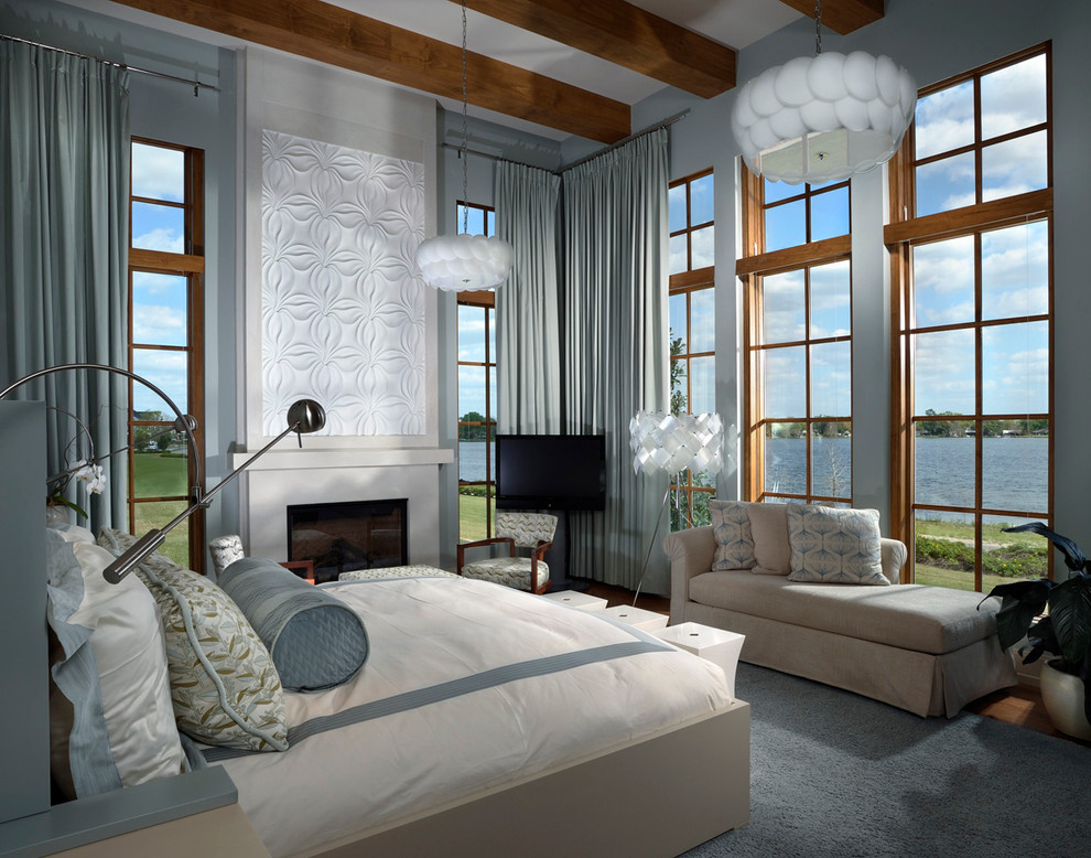 Imagen de dormitorio principal y televisión actual grande con paredes azules, todas las chimeneas, suelo de madera oscura, marco de chimenea de hormigón y suelo marrón