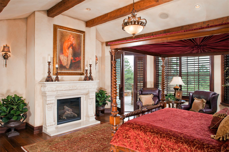 Example of a large classic master medium tone wood floor bedroom design in Denver with beige walls, a standard fireplace and a stone fireplace