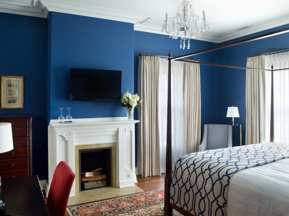 На фото: большая гостевая спальня (комната для гостей) в классическом стиле с синими стенами, стандартным камином, фасадом камина из плитки, паркетным полом среднего тона и коричневым полом с
