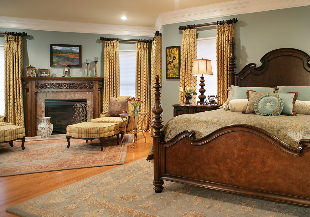 Klassisches Hauptschlafzimmer mit grauer Wandfarbe, braunem Holzboden, Kamin und Kaminumrandung aus Stein in New York