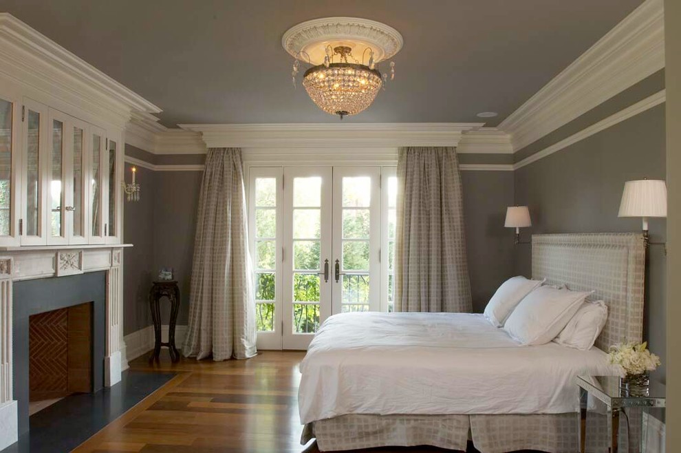 Klassisches Schlafzimmer mit grauer Wandfarbe, braunem Holzboden und Kamin in New York