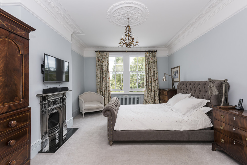 На фото: спальня в классическом стиле с серыми стенами, ковровым покрытием и стандартным камином с