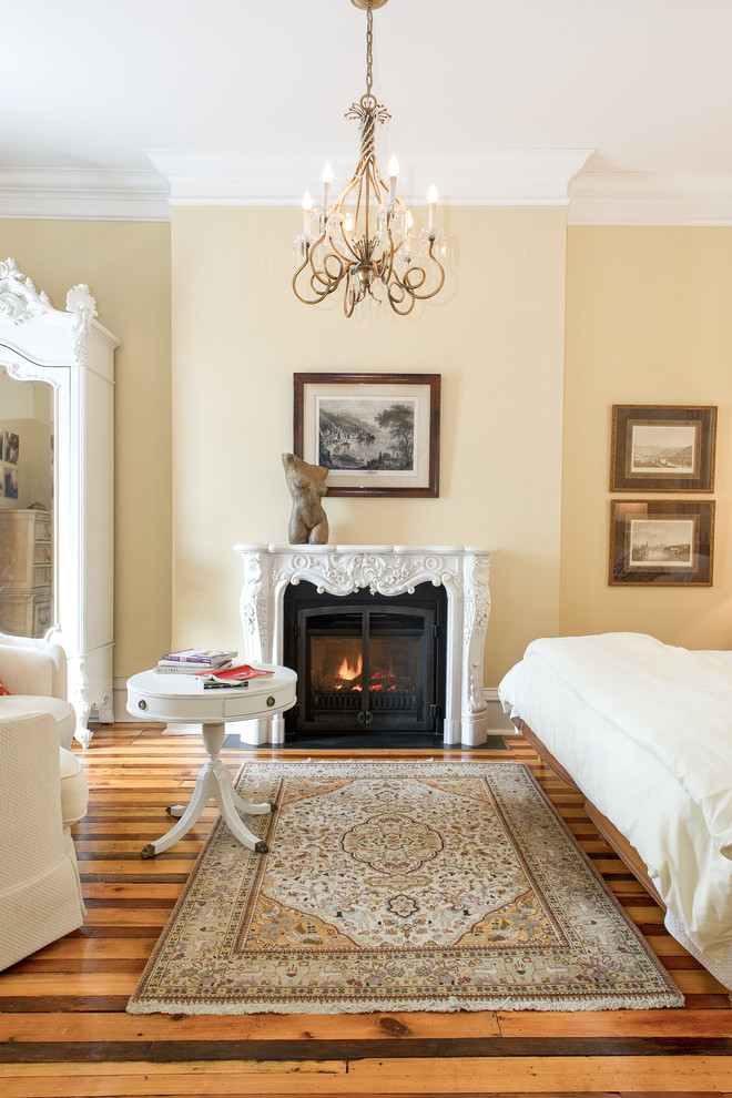 Esempio di una camera matrimoniale classica con pareti beige, pavimento in legno massello medio e camino classico