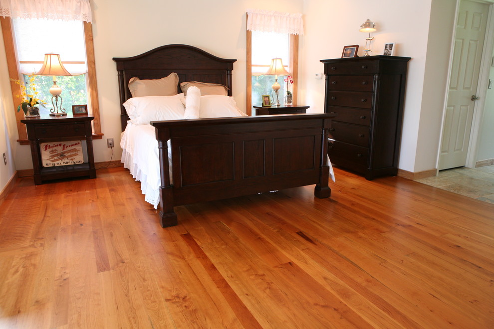 Aménagement d'une chambre parentale classique de taille moyenne avec un mur blanc, un sol en bois brun et aucune cheminée.