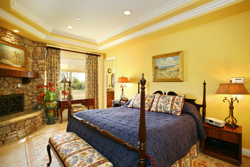 Mittelgroßes Klassisches Hauptschlafzimmer mit gelber Wandfarbe, Teppichboden, Eckkamin und Kaminumrandung aus Stein in San Diego