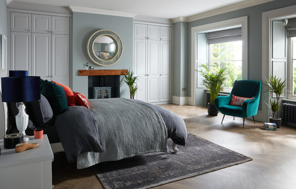 Foto di una camera da letto classica con pareti grigie, pavimento in legno massello medio, camino classico e pavimento marrone