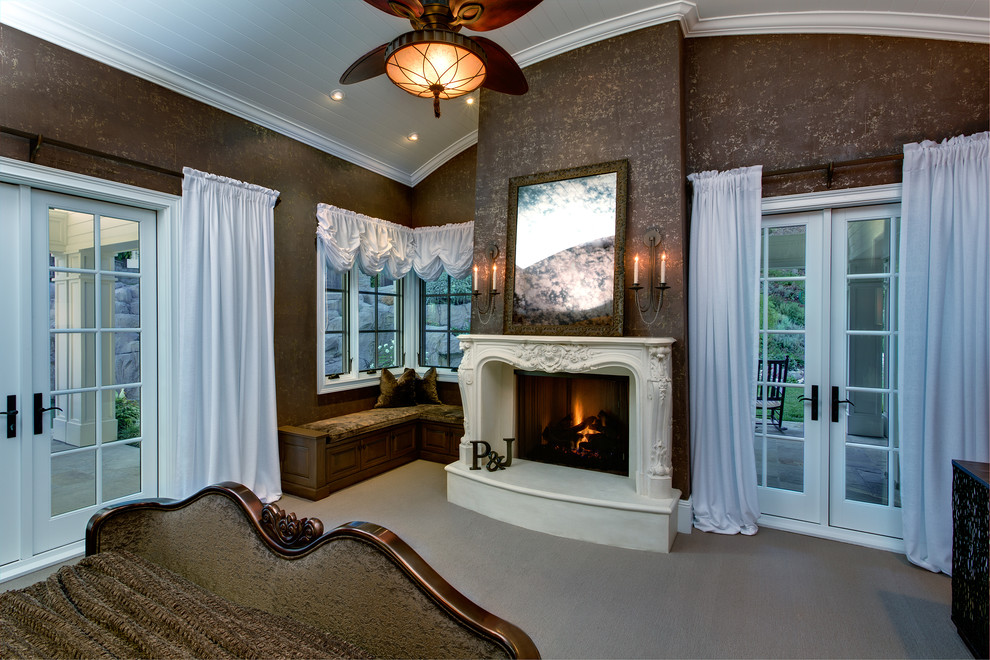 На фото: большая хозяйская спальня в классическом стиле с коричневыми стенами, ковровым покрытием, стандартным камином, фасадом камина из штукатурки и бежевым полом