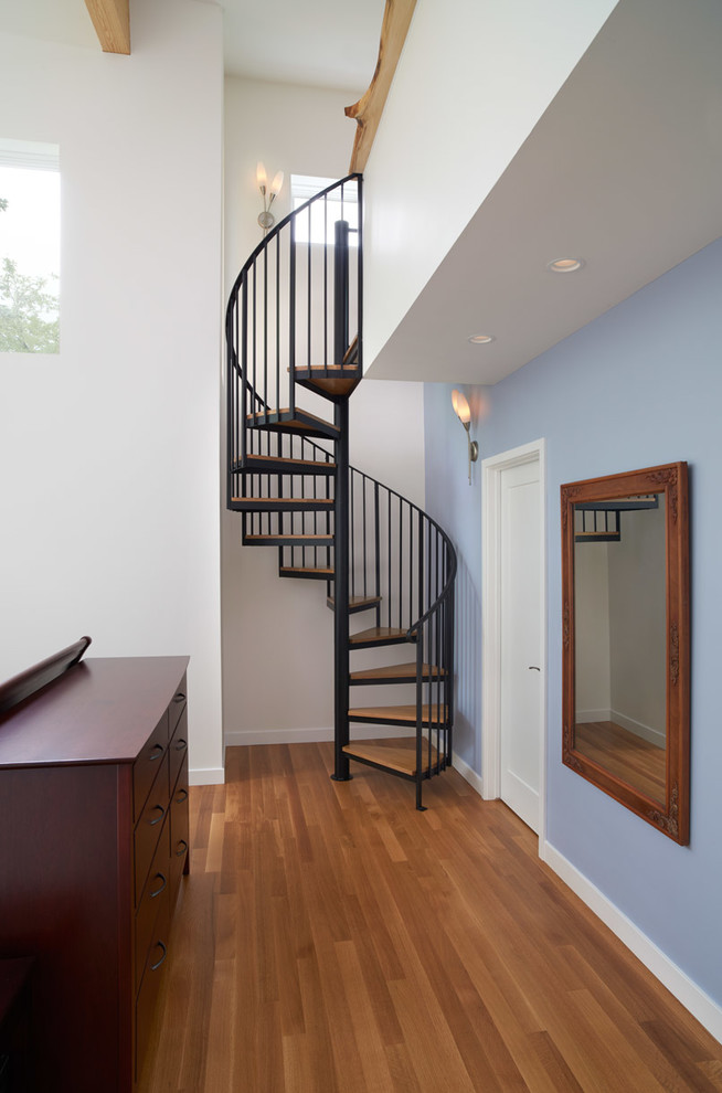 Cette photo montre une chambre parentale tendance de taille moyenne avec un sol en bois brun, aucune cheminée, un mur bleu et un sol marron.
