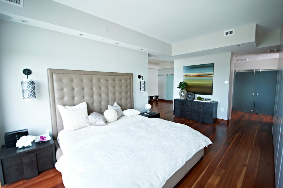 Modelo de dormitorio principal moderno extra grande con paredes grises y suelo de madera en tonos medios
