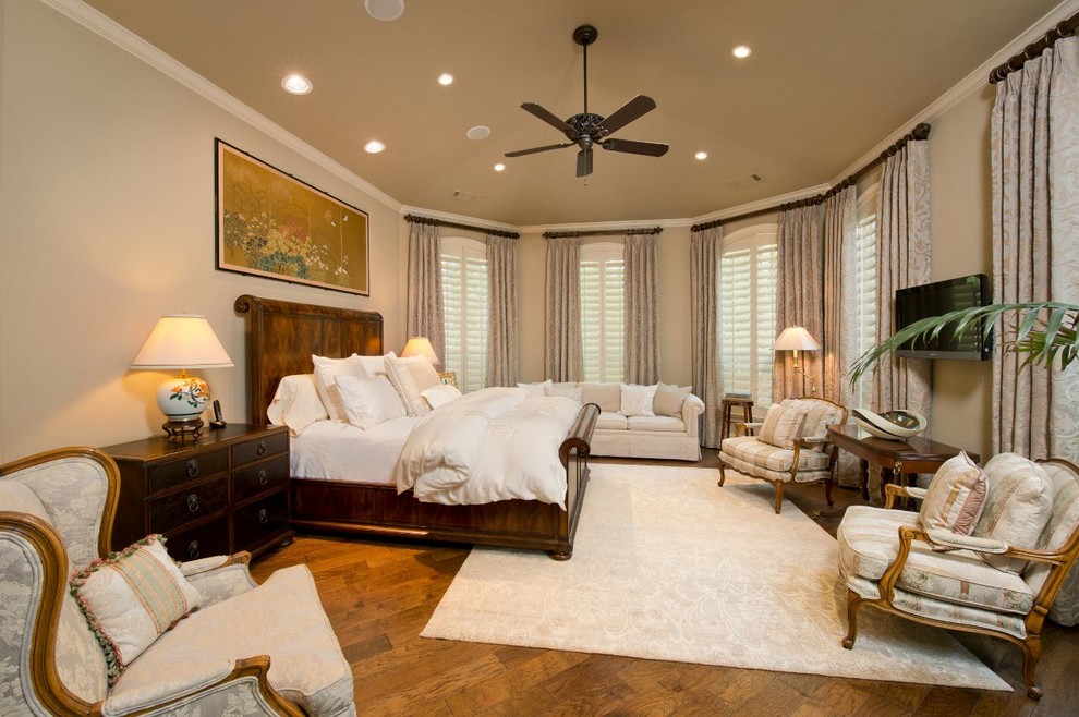 Modelo de dormitorio principal clásico grande con paredes beige, suelo de madera en tonos medios y suelo marrón