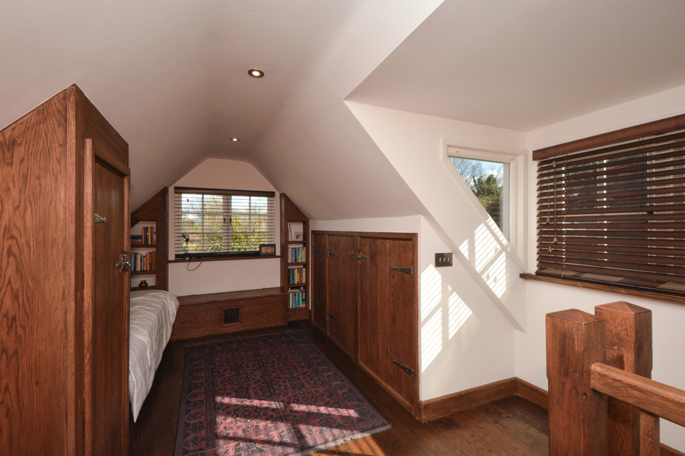 Modelo de dormitorio tipo loft de estilo de casa de campo pequeño sin chimenea con paredes blancas y suelo de madera oscura