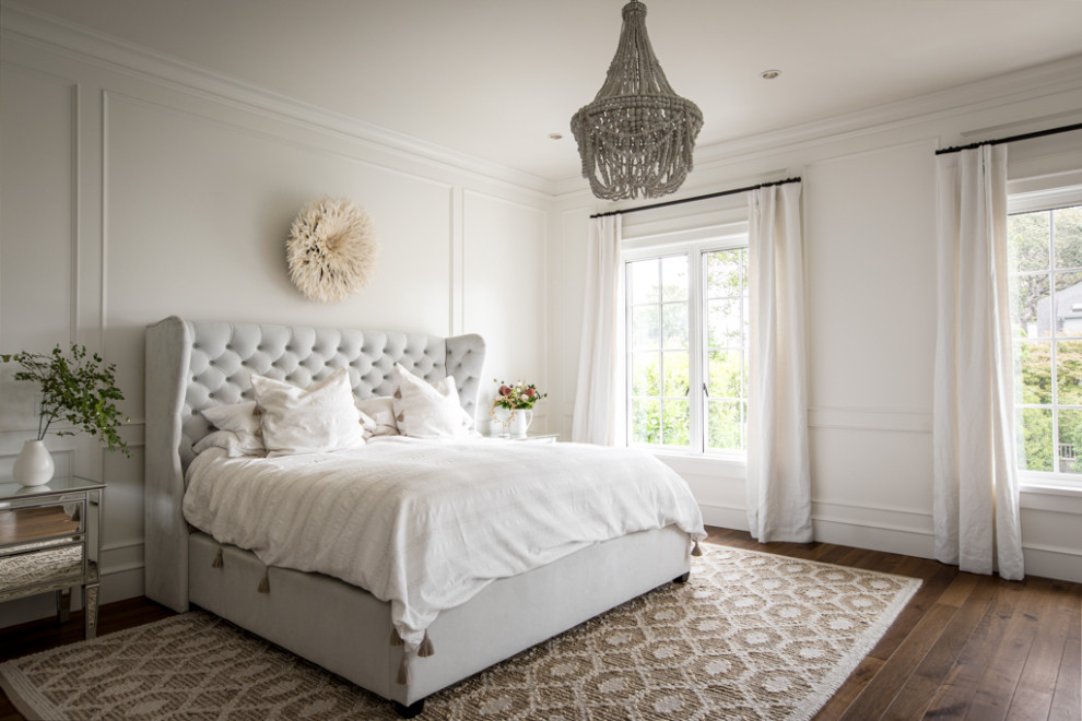 他の地域にある広いトランジショナルスタイルのおしゃれな主寝室 (白い壁、無垢フローリング、茶色い床、パネル壁) のインテリア