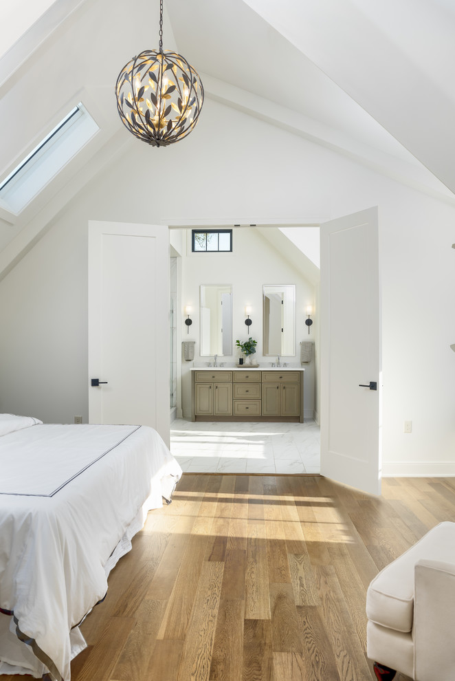 Ejemplo de dormitorio principal tradicional renovado de tamaño medio sin chimenea con paredes blancas, suelo de madera en tonos medios y suelo marrón