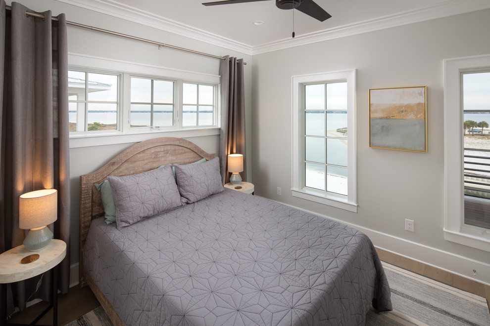 Diseño de habitación de invitados marinera grande sin chimenea con paredes grises, suelo de madera en tonos medios y suelo marrón