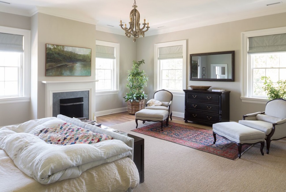 Geräumiges Klassisches Hauptschlafzimmer mit Kamin, grauer Wandfarbe, braunem Holzboden und Kaminumrandung aus Stein in Sonstige