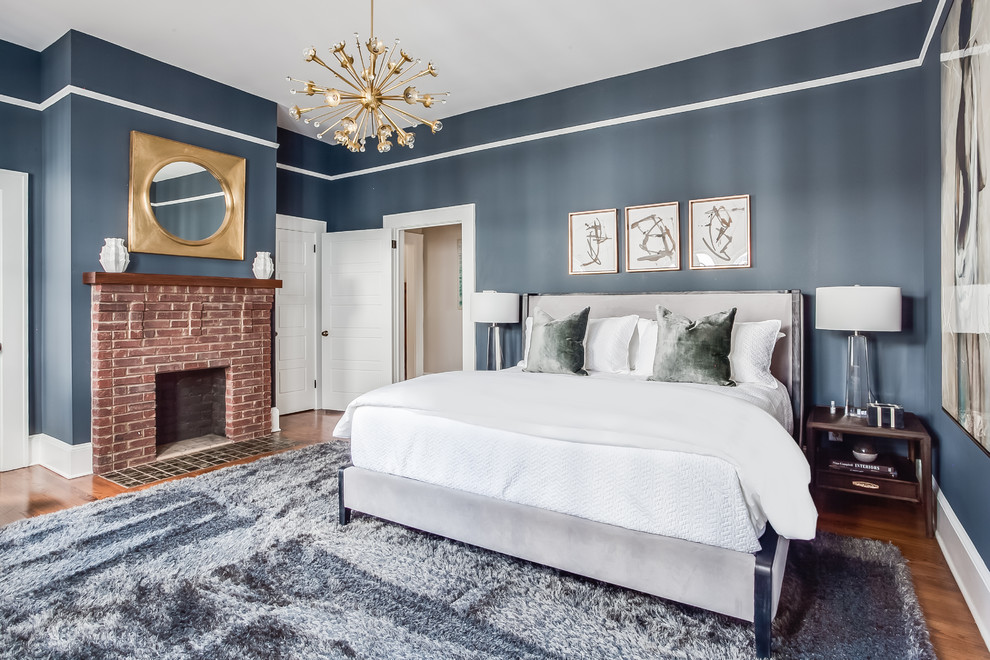 Inspiration för ett vintage sovrum, med blå väggar, mellanmörkt trägolv, en standard öppen spis, en spiselkrans i tegelsten och brunt golv