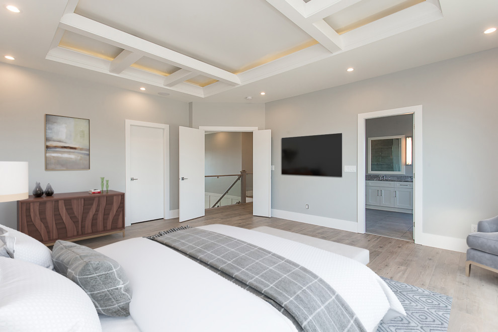 Imagen de dormitorio principal clásico renovado grande sin chimenea con paredes grises, suelo de madera clara y suelo beige