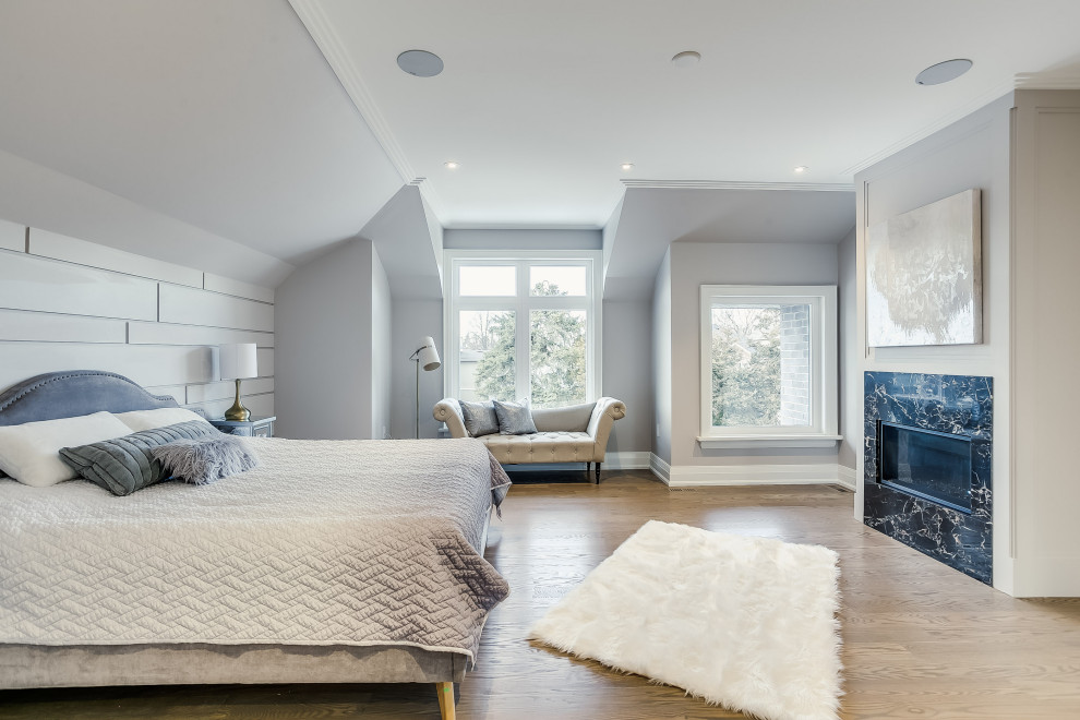 Klassisches Hauptschlafzimmer mit grauer Wandfarbe, braunem Holzboden, Gaskamin, Kaminumrandung aus Stein, braunem Boden und Wandpaneelen in Toronto