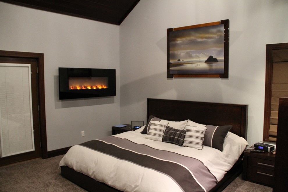 Cette photo montre une grande chambre chic avec un mur gris, un manteau de cheminée en métal et une cheminée ribbon.