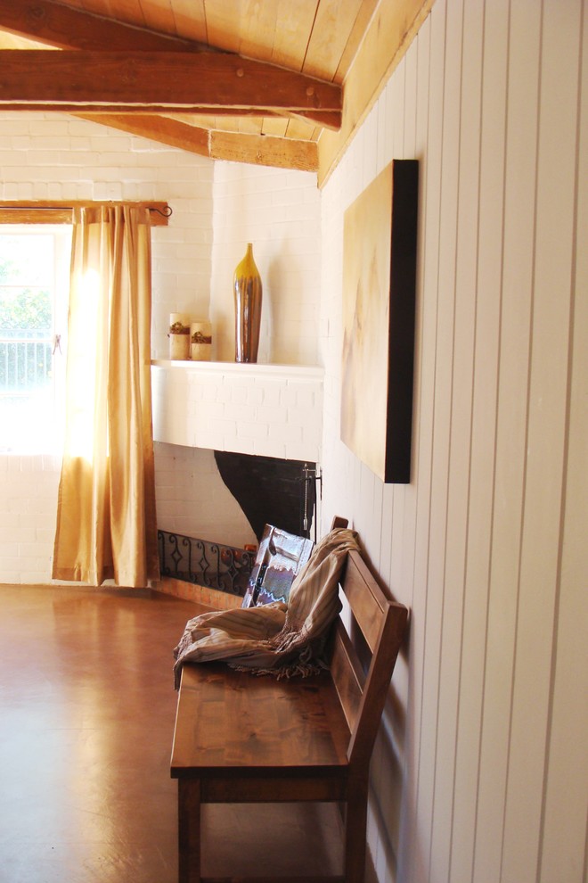 フェニックスにある中くらいなトランジショナルスタイルのおしゃれな主寝室 (白い壁、コンクリートの床、コーナー設置型暖炉、レンガの暖炉まわり)