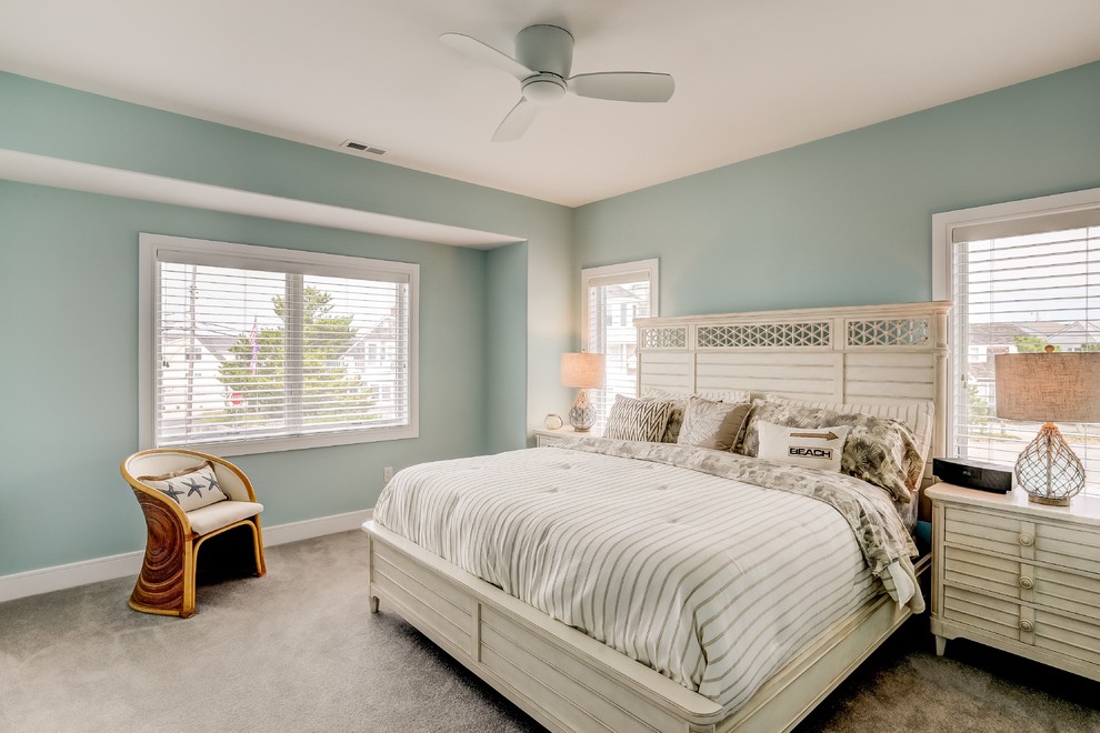 Design ideas for a beach style guest bedroom in New York with blue walls, carpet and brown floors.