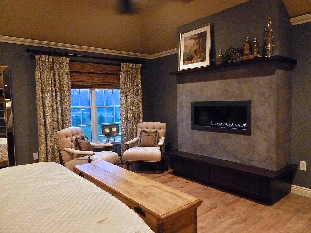 Imagen de dormitorio principal tradicional renovado grande con suelo de madera clara, chimenea lineal, marco de chimenea de yeso y paredes azules
