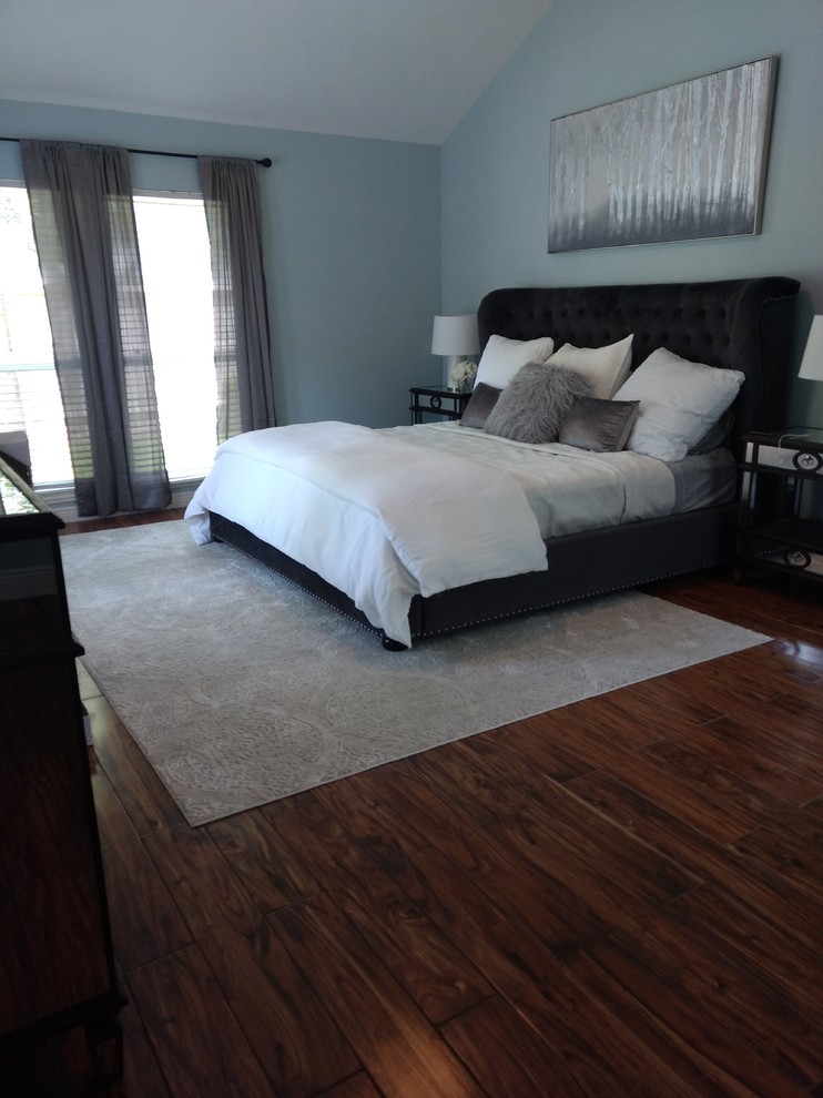 Large traditional master bedroom in Houston with blue walls, dark hardwood flooring, no fireplace and brown floors.