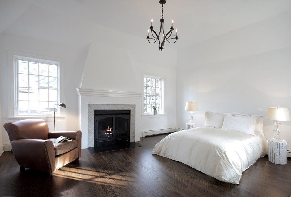 Aménagement d'une grande chambre parentale classique avec un mur blanc, parquet foncé, une cheminée standard et un manteau de cheminée en métal.