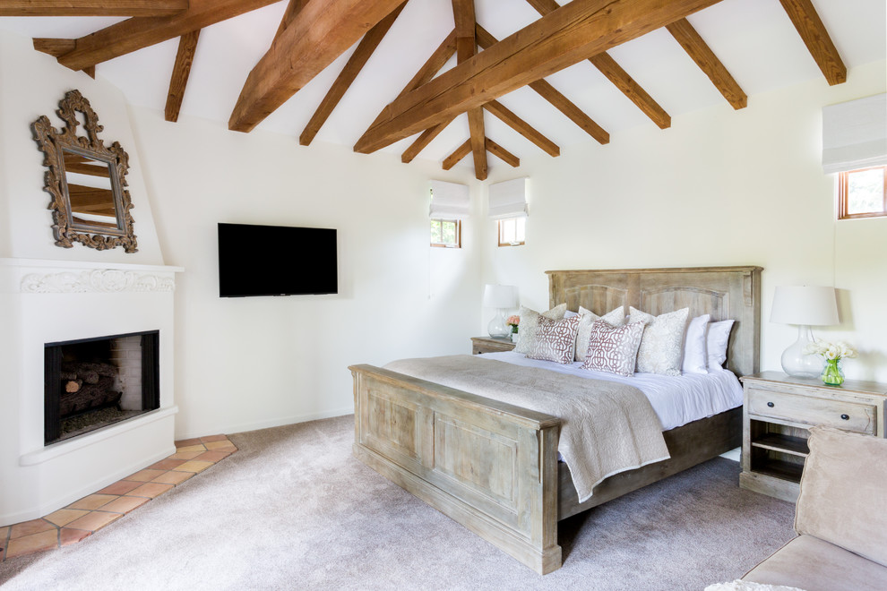 На фото: хозяйская спальня среднего размера в стиле фьюжн с белыми стенами, ковровым покрытием, угловым камином, фасадом камина из штукатурки и серым полом