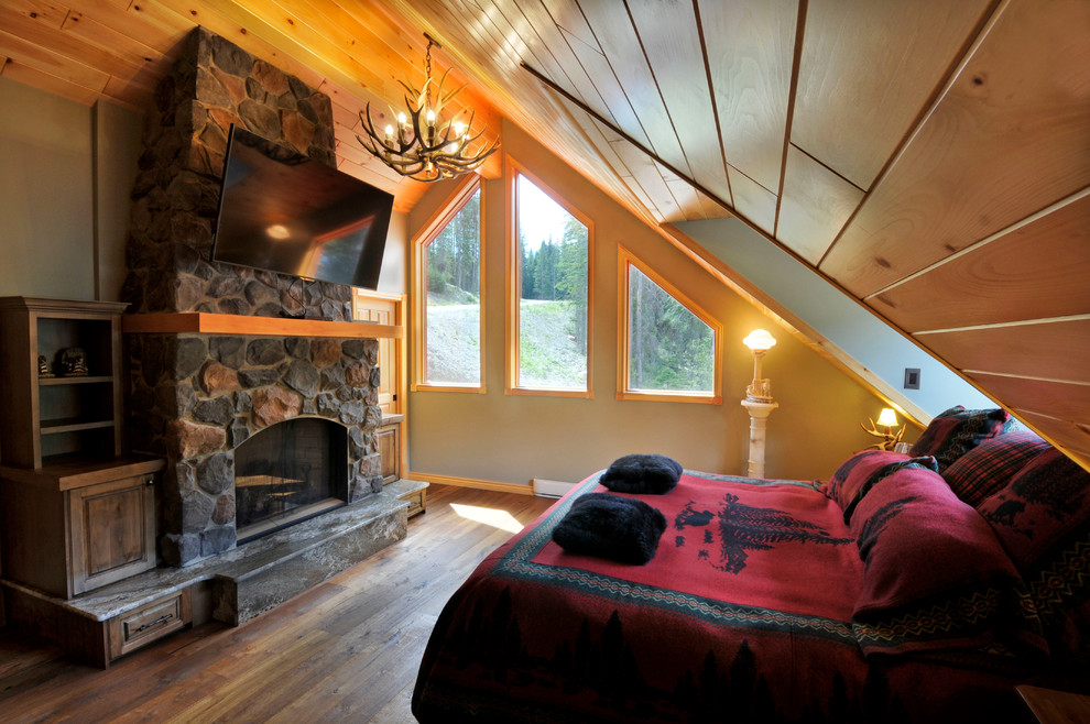 Mittelgroßes Rustikales Hauptschlafzimmer mit beiger Wandfarbe, dunklem Holzboden, Kamin, Kaminumrandung aus Stein und braunem Boden in Vancouver