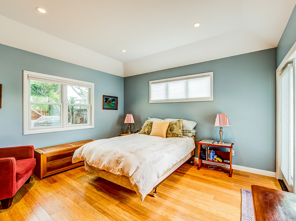 Modelo de dormitorio principal costero de tamaño medio con paredes azules y suelo de madera clara