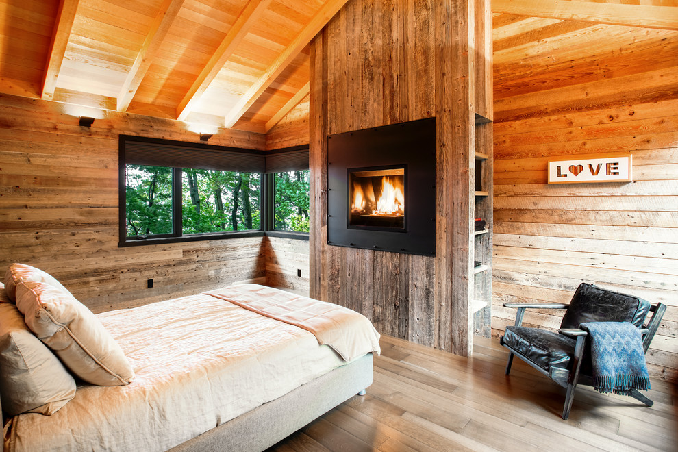 Modelo de dormitorio rústico con suelo de madera clara, todas las chimeneas, marco de chimenea de metal y suelo beige