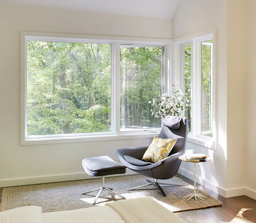 Cette image montre une chambre d'amis design de taille moyenne avec un mur beige et un sol en bois brun.