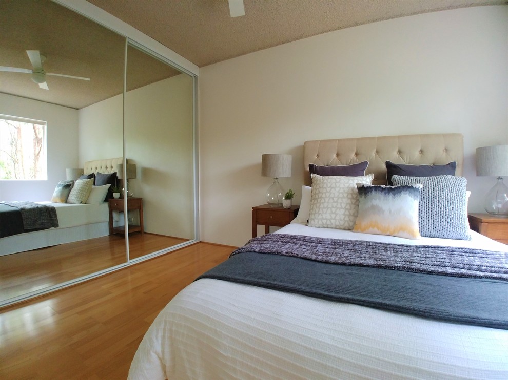 Foto de dormitorio principal actual pequeño con paredes blancas, suelo laminado y suelo marrón