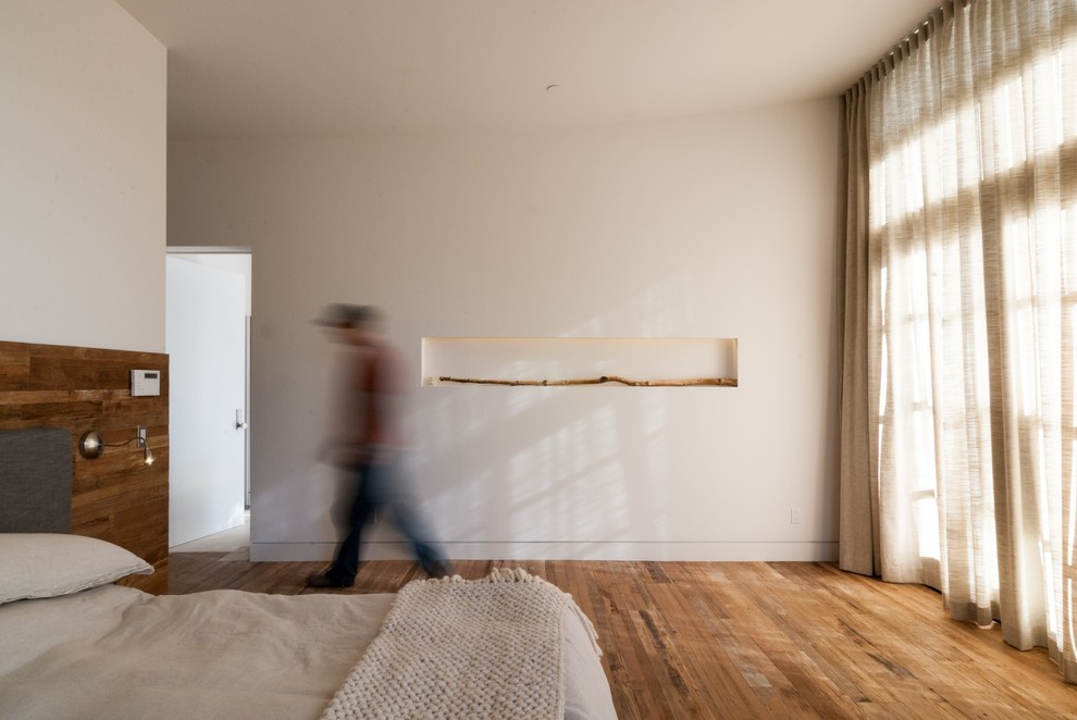На фото: хозяйская спальня среднего размера в стиле модернизм с белыми стенами и светлым паркетным полом без камина с