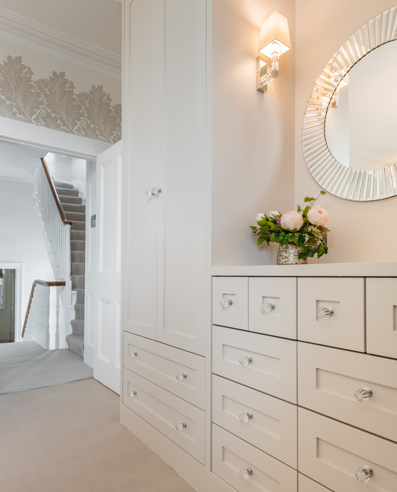 Modelo de dormitorio principal clásico renovado pequeño con paredes beige, moqueta, estufa de leña, marco de chimenea de piedra y suelo beige