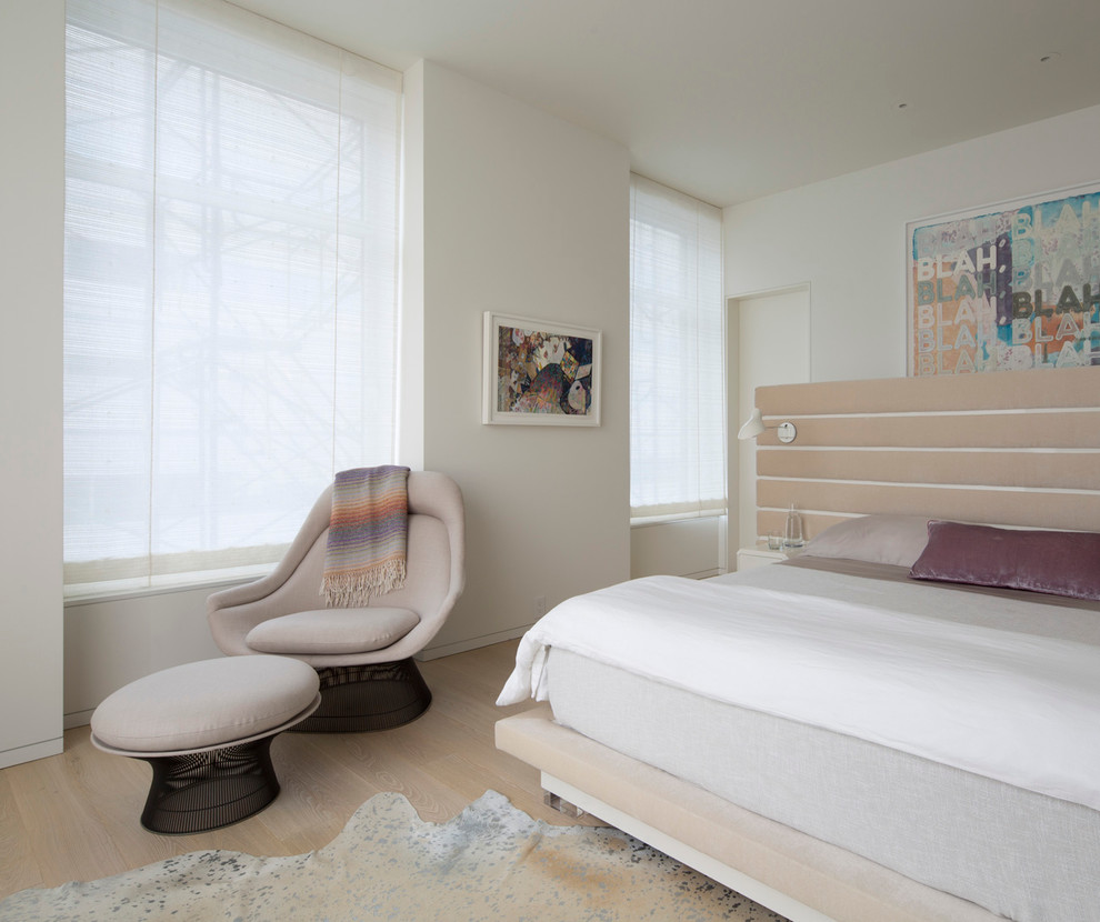 Photo of a contemporary bedroom in New York with white walls and medium hardwood flooring.