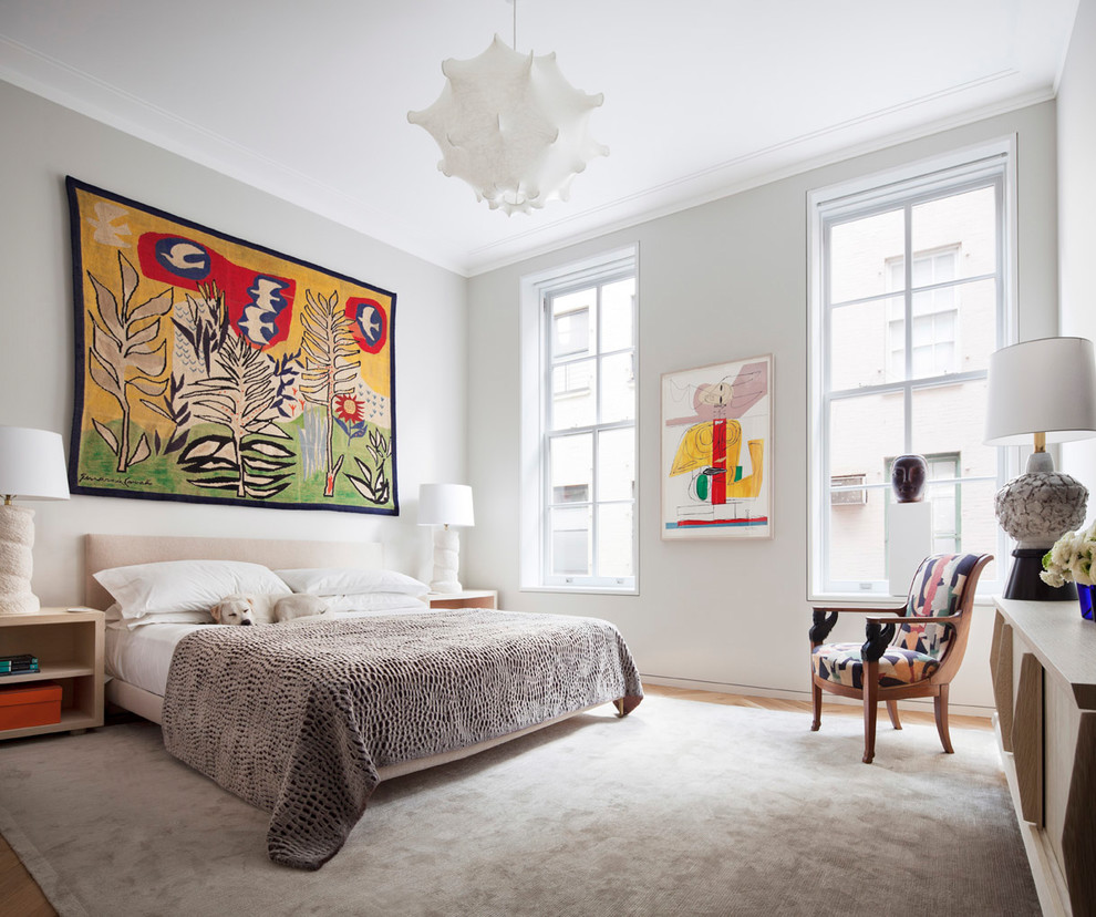 Trendy medium tone wood floor and brown floor bedroom photo in New York with white walls