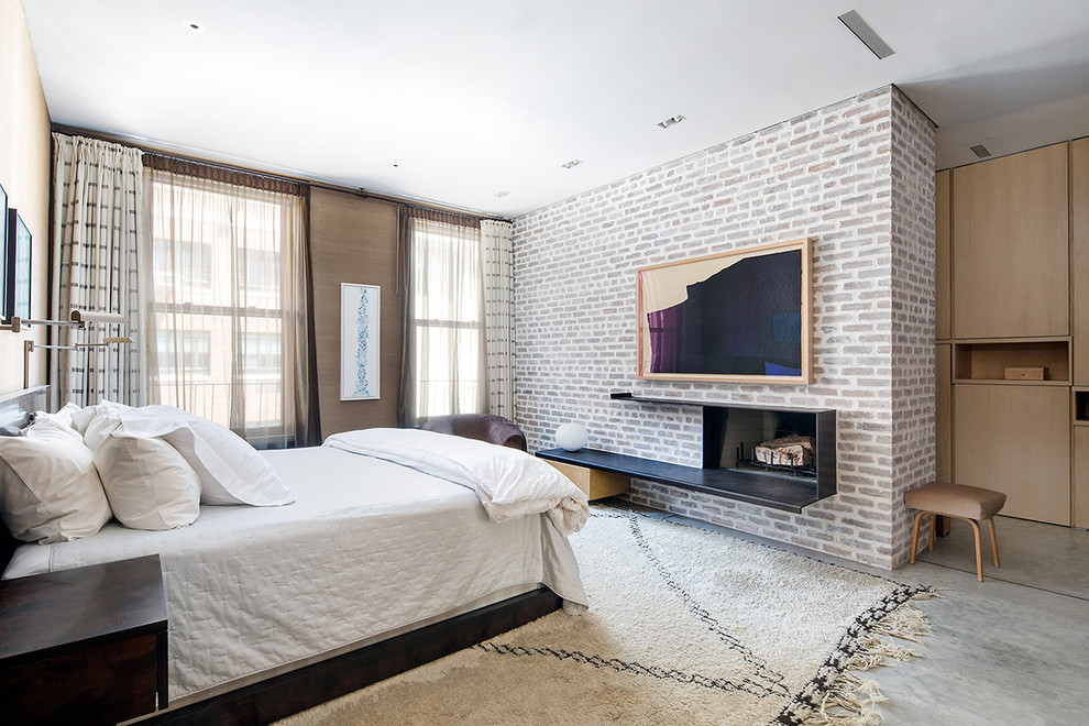 Imagen de dormitorio principal contemporáneo con suelo de cemento, chimenea lineal y marco de chimenea de metal