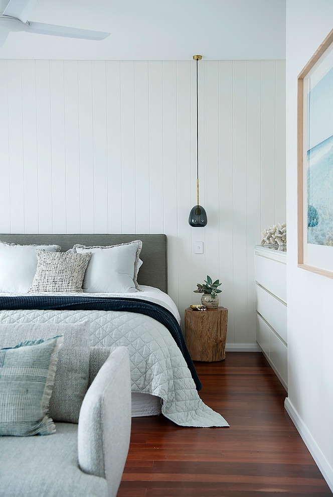 Bild på ett maritimt sovrum, med vita väggar, mellanmörkt trägolv och brunt golv