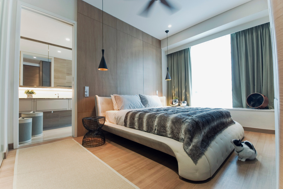This is an example of a contemporary bedroom in Singapore with light hardwood flooring.