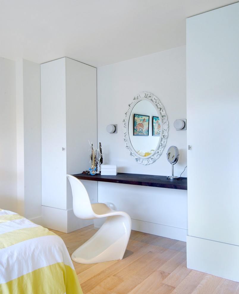 Foto di una camera da letto design con pareti bianche, parquet chiaro e angolo studio