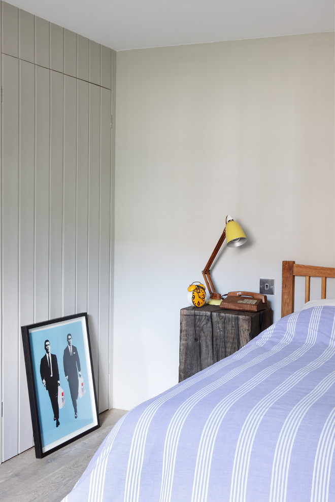 This is an example of a small classic bedroom in London with beige walls and medium hardwood flooring.