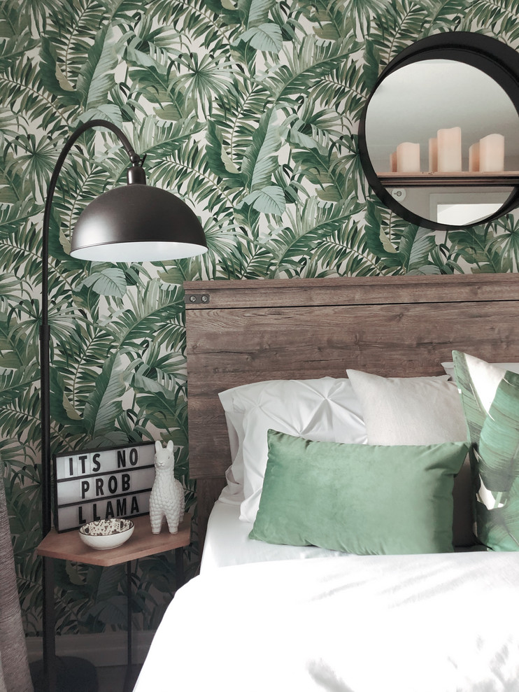 Immagine di una piccola camera matrimoniale tropicale con pareti verdi, pavimento in laminato, nessun camino e pavimento grigio