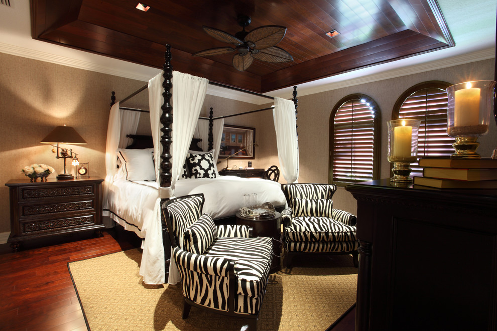 Modelo de dormitorio tropical grande sin chimenea con paredes marrones y suelo de madera oscura